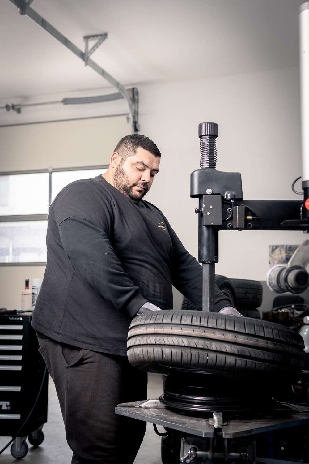 Mechaniker beim aufziehen eines Reifens auf die Felge im Rahmen eines Reifenwechsels